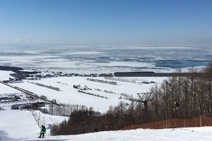 スキー場の山の上から見える雪景色とオホーツク海に広がる流氷の写真
