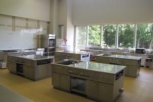 調理台があり、前方にはホワイトボードが置かれている料理実習室の写真