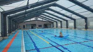 屋内の25メートルプールとブールの中で水泳を楽しんでいる人が写っているウトロ地域水泳プールの写真