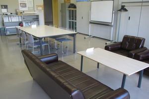 6人用の机と椅子、ソファーセット、壁際にはホワイトボードなどが置かれている団体活動室