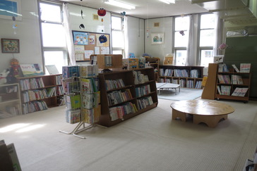 絵本コーナー。絨毯が敷かれ、背の低い本棚や座卓が並ぶ。